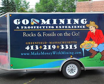 The GoMining trailer graphic featuring a man sifting for gems and contact information